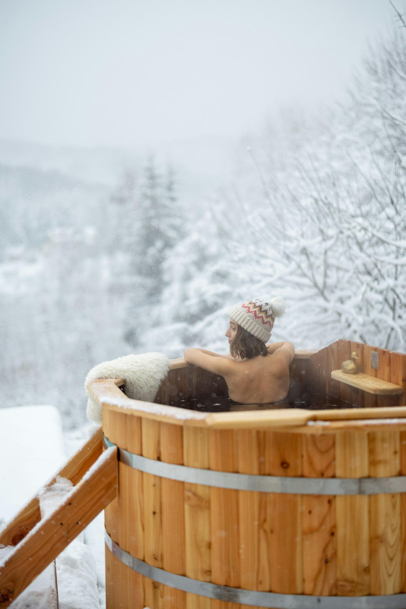 Woman relaxing in hot bath at snowy mountains